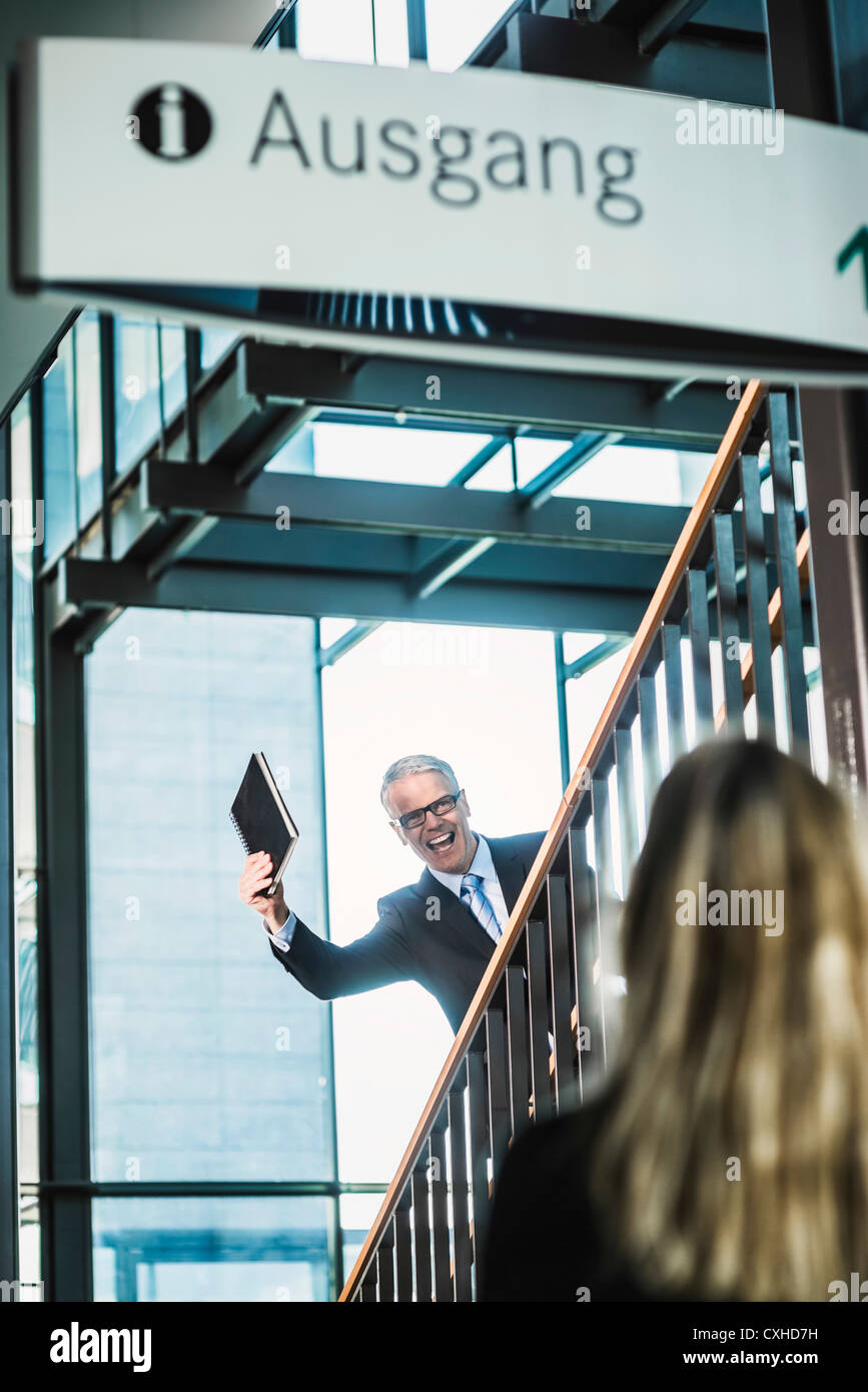 Germany, Stuttgart, Businessman showing diary to woman on stairs of office building Stock Photo