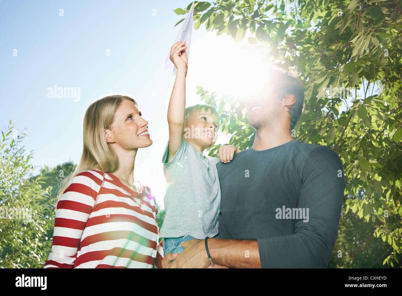 Germany, Cologne, Family playing with paper plane, smiling Stock Photo