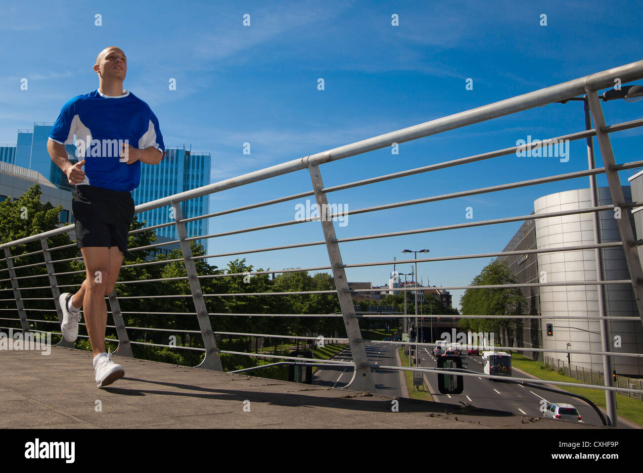 Germany, NorthRhineWestphalia, Duesseldorf, Young man running, city in background Stock Photo