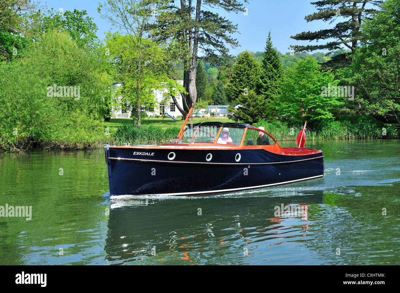 Couple cruising on a gentlemans motor yacht or motorboat on the Upper Reaches of the River Thames at Pangbourne, Berkshire, England, UK Stock Photo