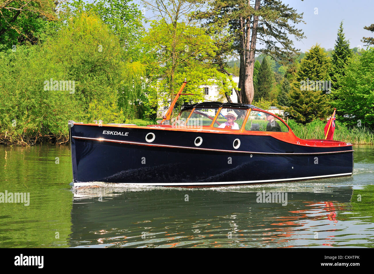 Couple cruising on a gentlemans motor yacht or motorboat on the Upper Reaches of the River Thames at Pangbourne, Berkshire, England, UK Stock Photo