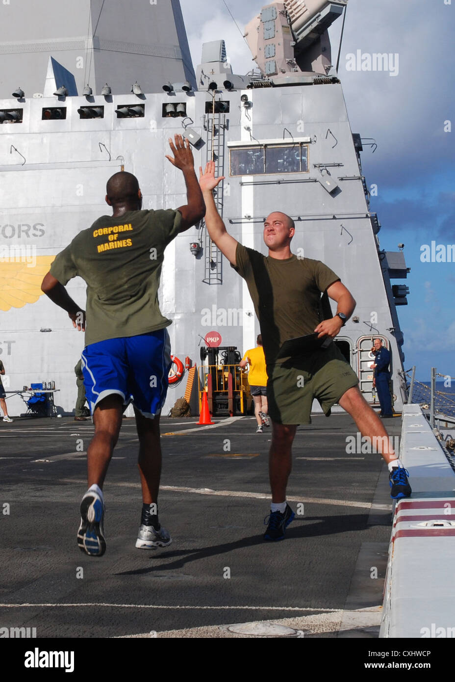 Cpl. Jonathan Clark high fives Cpl. Michael Valentinewilliams as he completes another lap during the Landaker 5k held by the “Purple Foxes” of Marine Medium Helicopter Squadron (HMM) 364 (REIN) aboard amphibious transport dock ship USS Green Bay (LPD 20). Green Bay is part of the Peleliu Amphibious Ready Group currently underway on a Western Pacific deployment with amphibious assault ship USS Peleliu (LHA 5) and amphibious dock landing ship USS Rushmore (LSD 47). Stock Photo
