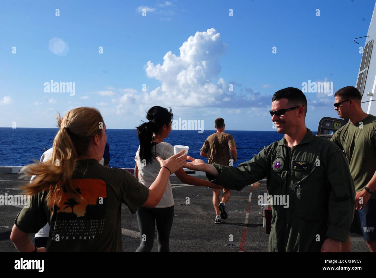 Capt. Paige Stull grabs a cup of water from Capt. Buckshot Mattson during the Landaker 5k held by the â€œPurple Foxesâ€ of Marine Medium Helicopter Squadron (HMM) 364 (REIN) aboard amphibious transport dock ship USS Green Bay (LPD 20). Green Bay is part of the Peleliu Amphibious Ready Group currently underway on a Western Pacific deployment with amphibious assault ship USS Peleliu (LHA 5) and amphibious dock landing ship USS Rushmore (LSD 47). Stock Photo