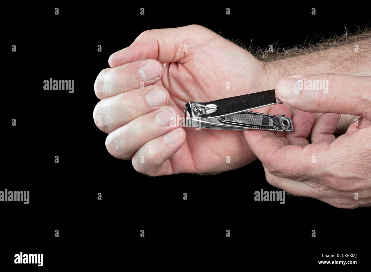 A man trims his fingernails using a metallic pair of nail clippers. Stock Photo