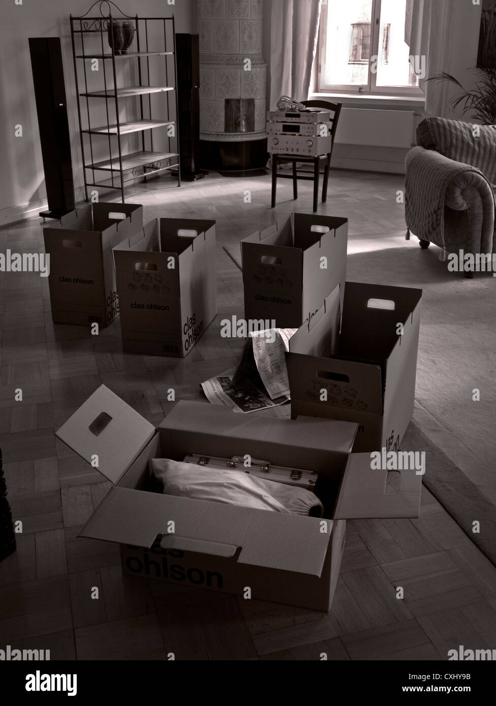 HOUSE MOVE PACKING CASES REMOVALS REPOSESSION Cardboard packing boxes with personal effects in living room during a house pack and move (B&W) Stock Photo
