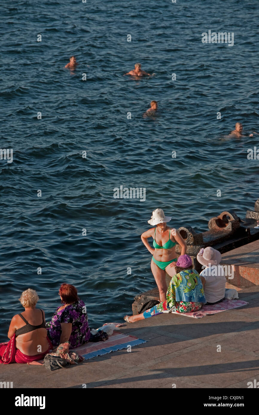 Swimmers on waterfront promenade of Sevastopol Harbor in summer. Stock Photo