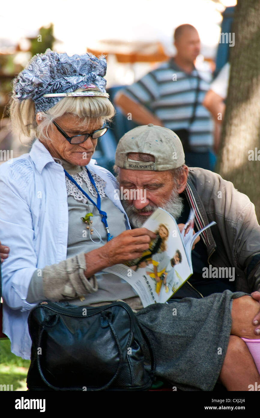 Elderly homeless couple sharing a literary moment in an Odessa park. Stock Photo