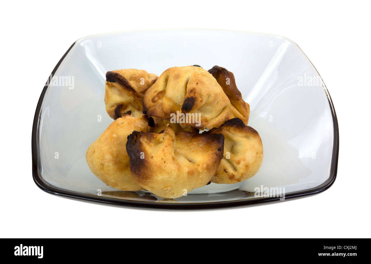 Several overly cooked crab Rangoon's in a translucent dish on a white background. Stock Photo