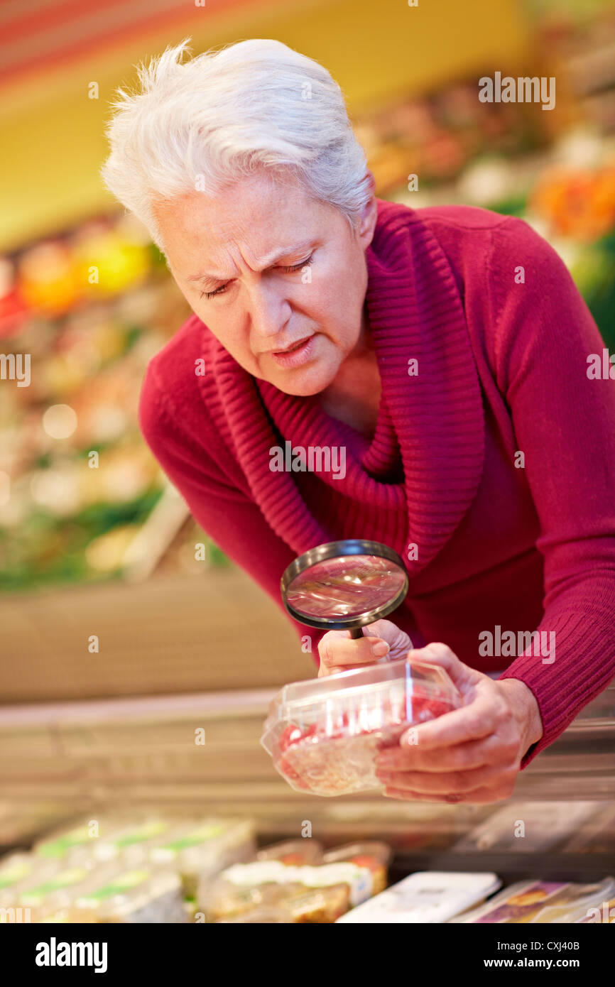 Germany, Cologne, Mature woman with raspberries and loupe in ...