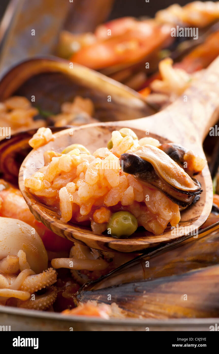 Seafood Paella with mussels, shrimps, calmari and wooden spoon as closeup in a pan Stock Photo