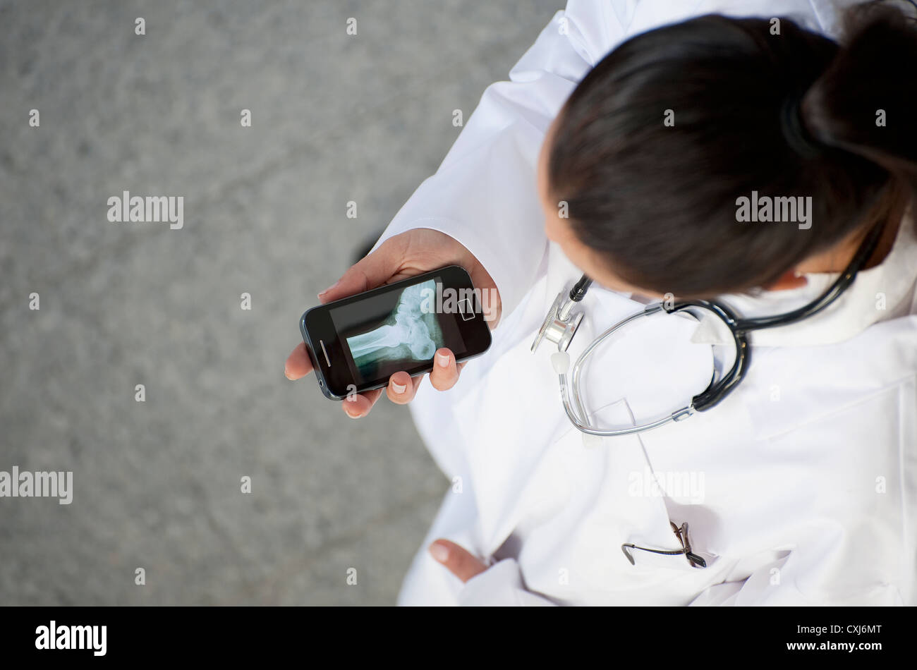 female doctor looking at x-ray on a smartphone Stock Photo
