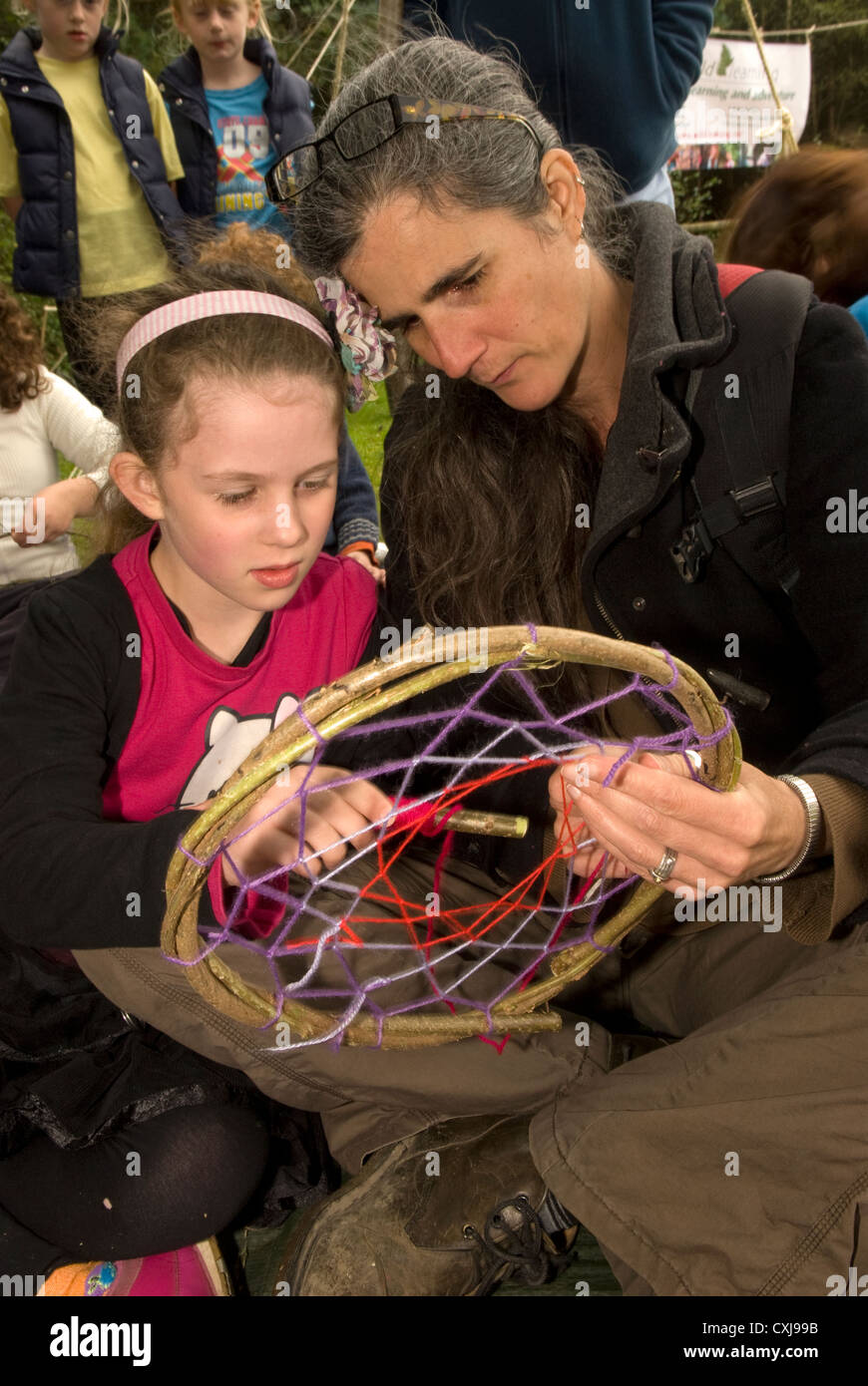 6 year old girl with her mother learning how to weave a 'dream catcher' at a Forestry Commission Discovery Day Stock Photo