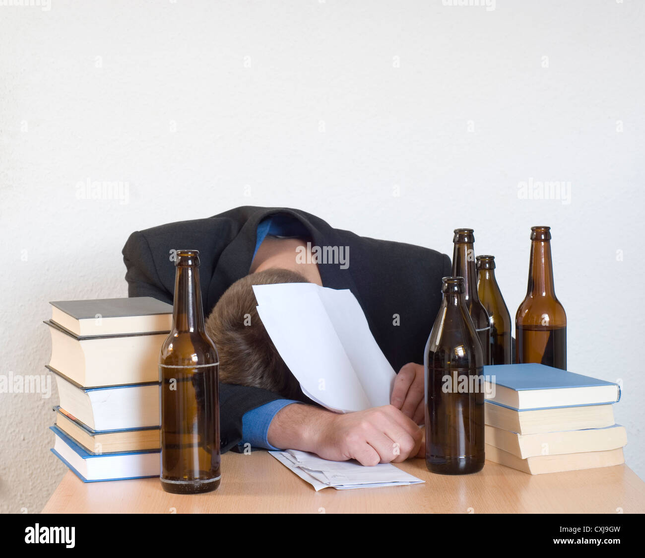 Exhauested Businessman Sleeping At His Desk Surrounded By Books