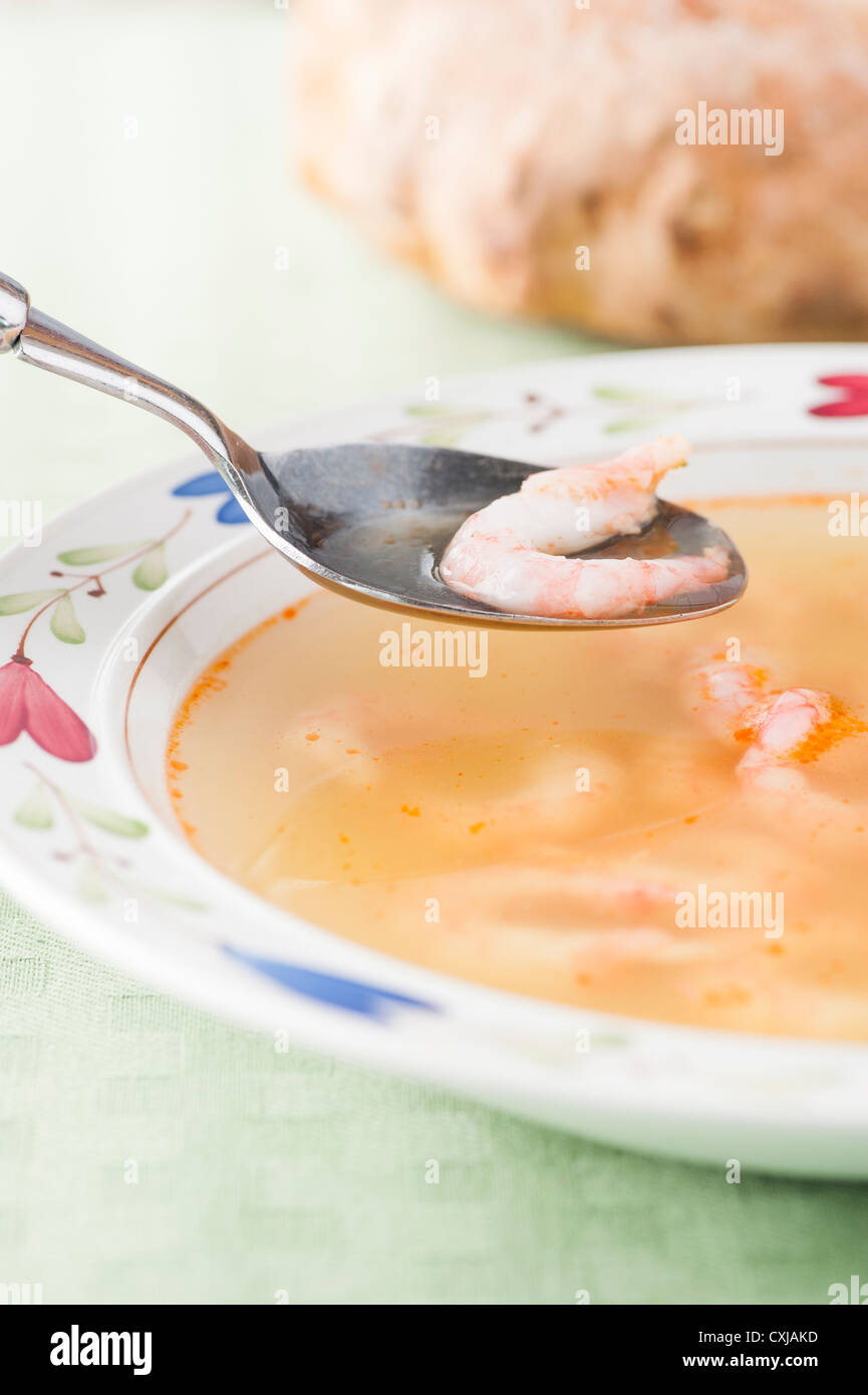 Bowl of warm soup with prawns and broth served with bread Stock Photo