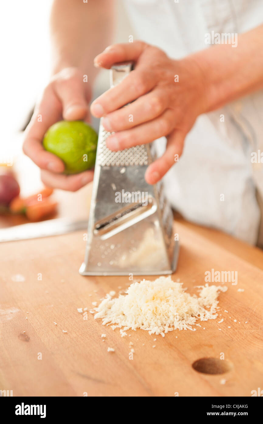 Grated horseradish on a cuttingboard with a chef grating lime peel in the background Stock Photo