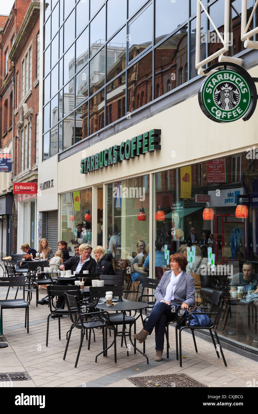 People sitting on outside seating in Starbucks coffee shop in the city centre at Arthur Square, Belfast, County Antrim, Northern Ireland, UK Stock Photo
