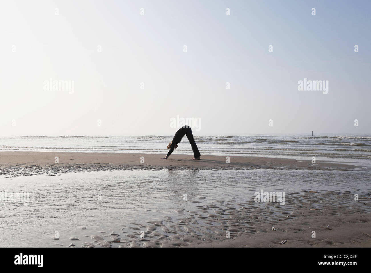 Belgium, Young woman exercising at North Sea Stock Photo