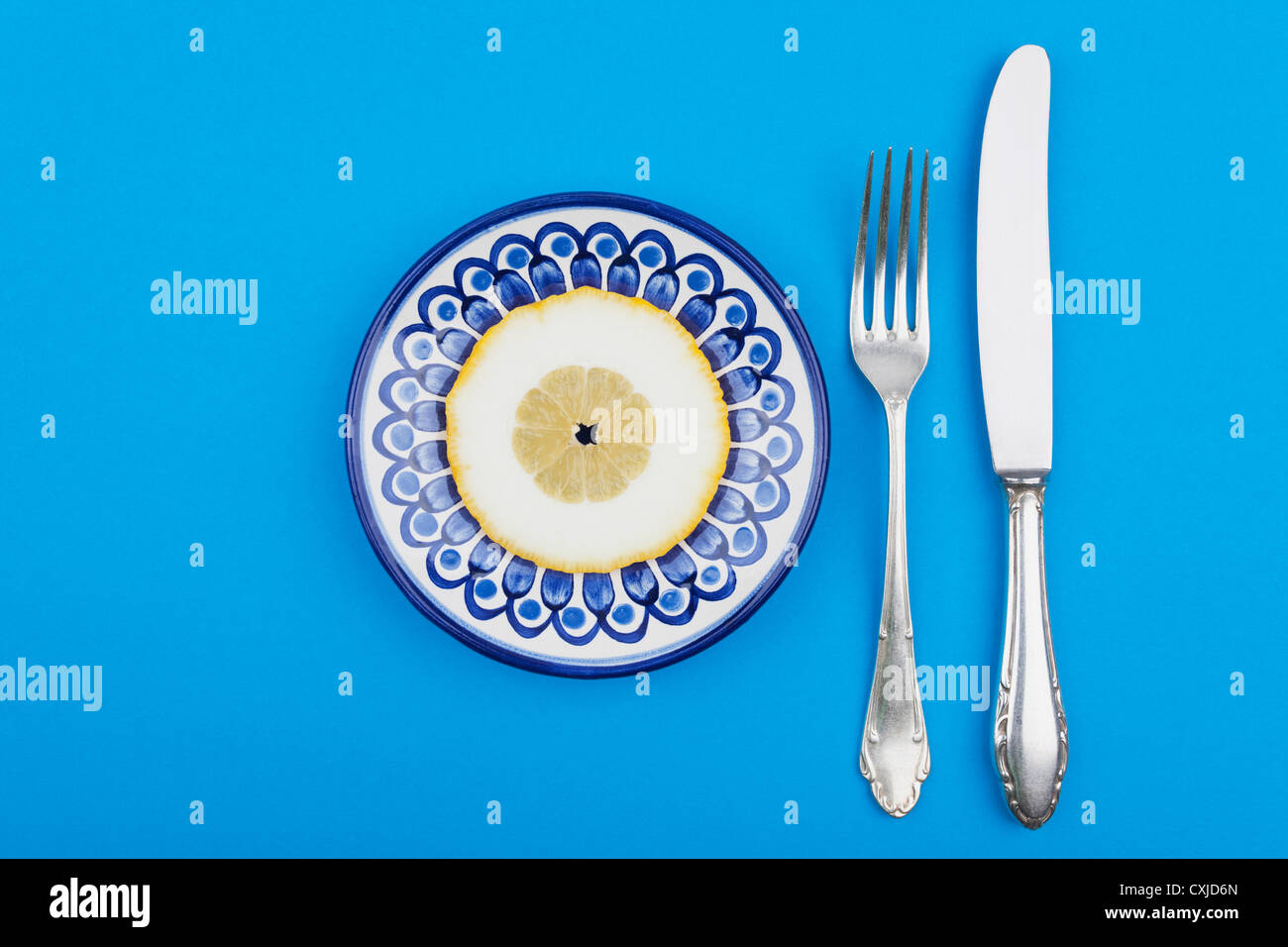 Lemon slice on plate with fork and knife Stock Photo