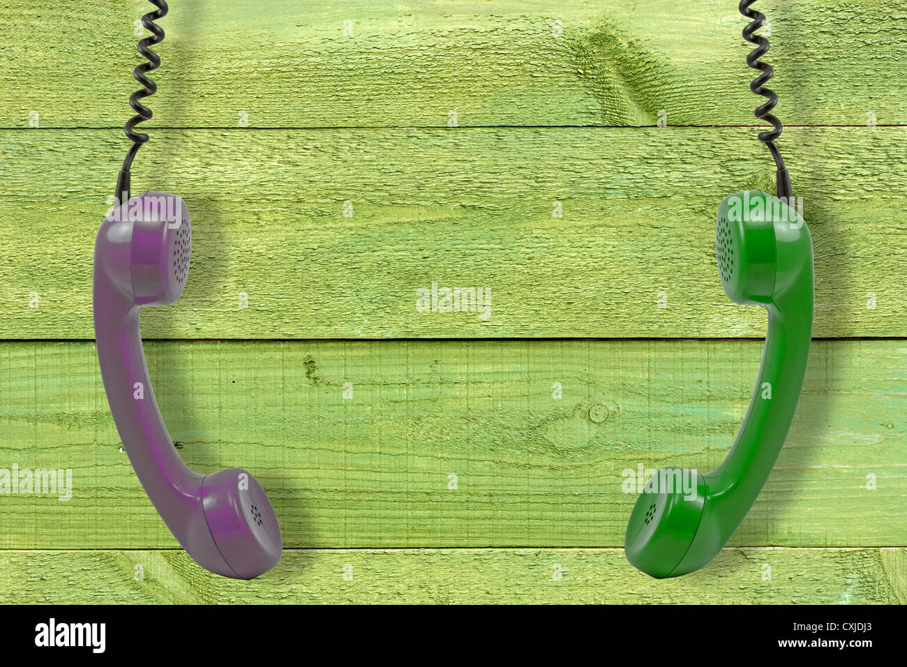 Two retro handsets hung against green painted wall Stock Photo