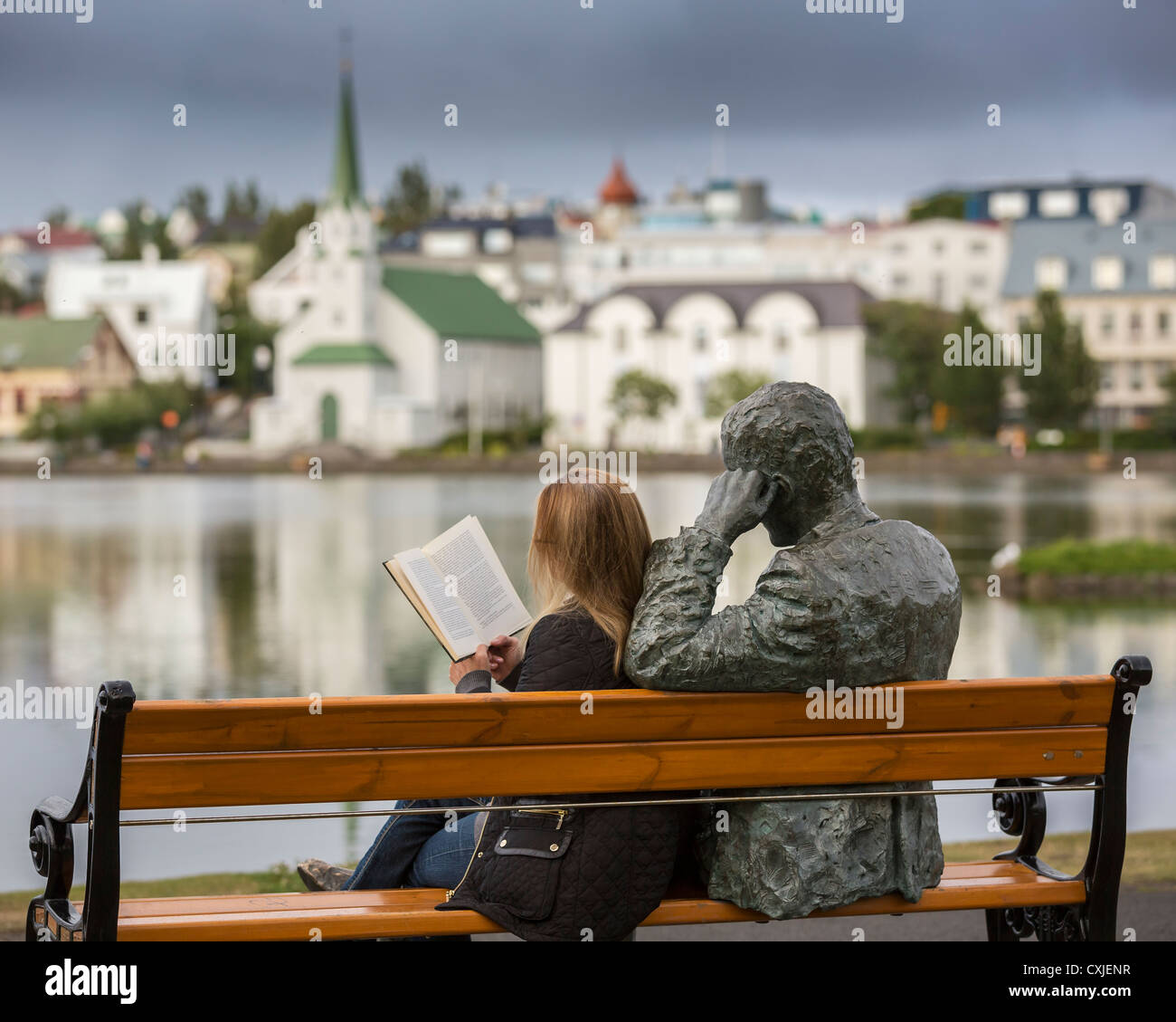 Woman reading next to statue of an Icelandic poet Tomas Gudmundsson, Reykjavik, Iceland. Stock Photo