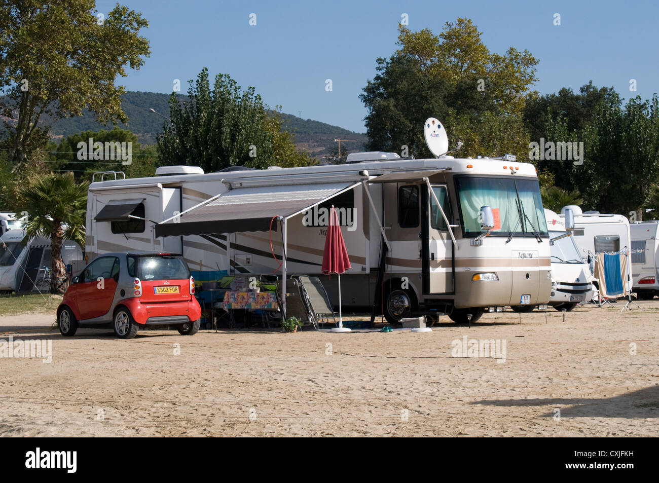 A large motor home is parked with a Smart car in a campsite by the edge of Grimaud beach. Stock Photo