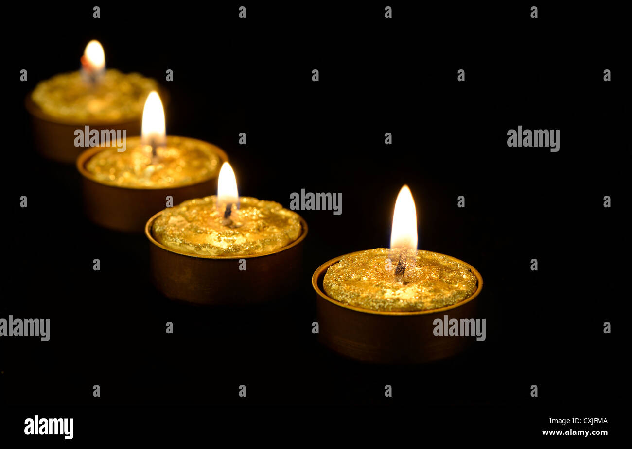 Golden burning candles on a black background Stock Photo - Alamy