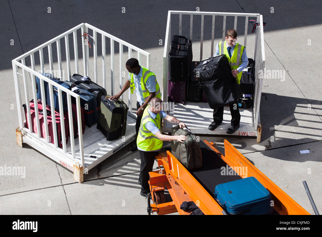 Baggage handlers loading cases on to conveyor belt to be loaded onto