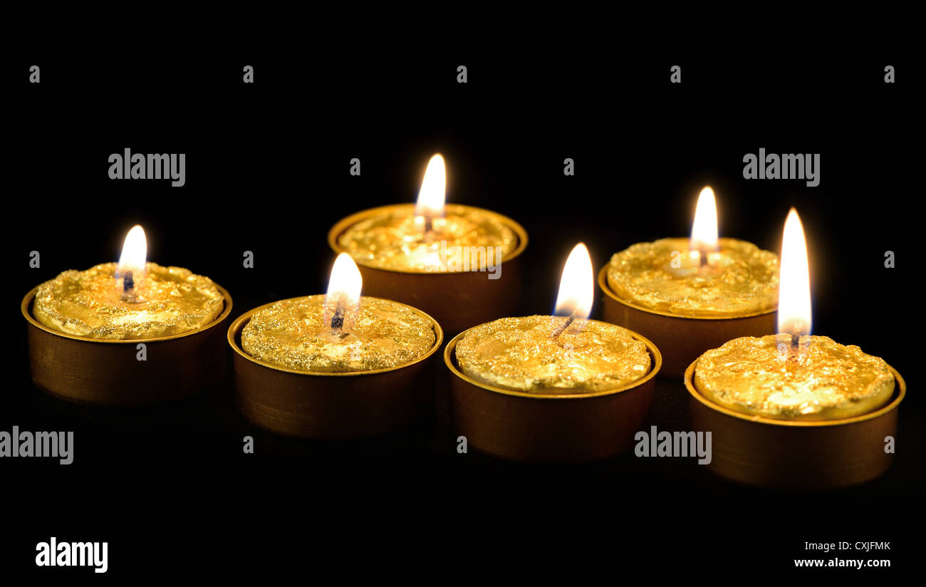Golden burning candles on a black background Stock Photo - Alamy