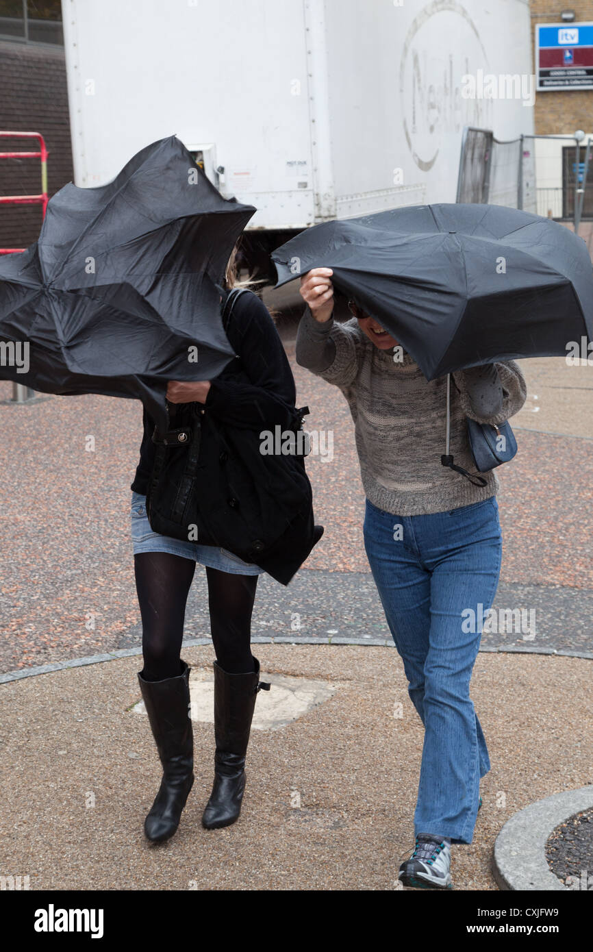 Two women fight the wind with their umbrellas during Thames Festival Stock Photo