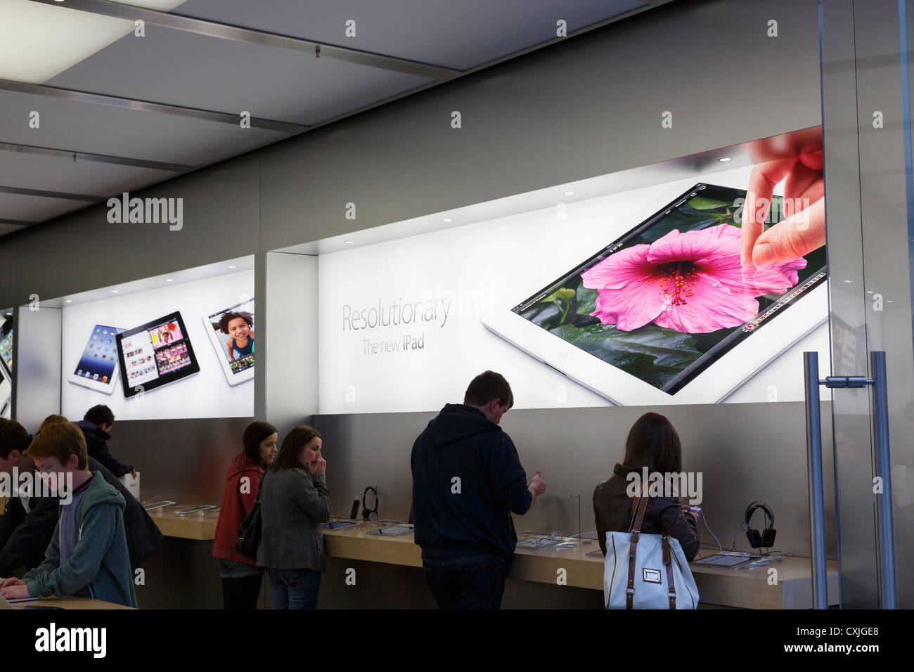 View of advertisement for new iPad 5 through door to Apple computer store with customers inside. UK Stock Photo