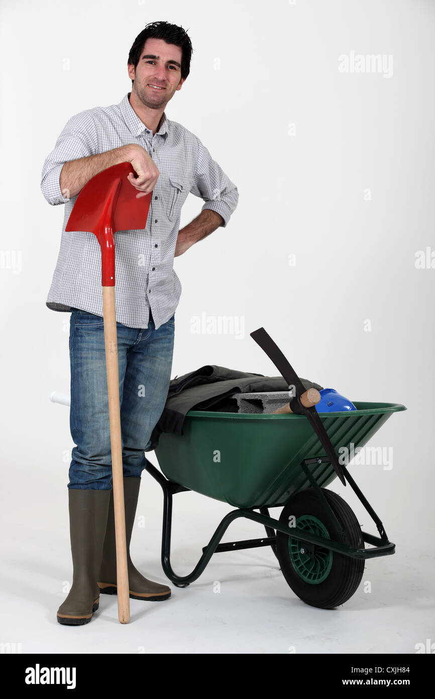Man stood with spade and wheelbarrow Stock Photo - Alamy