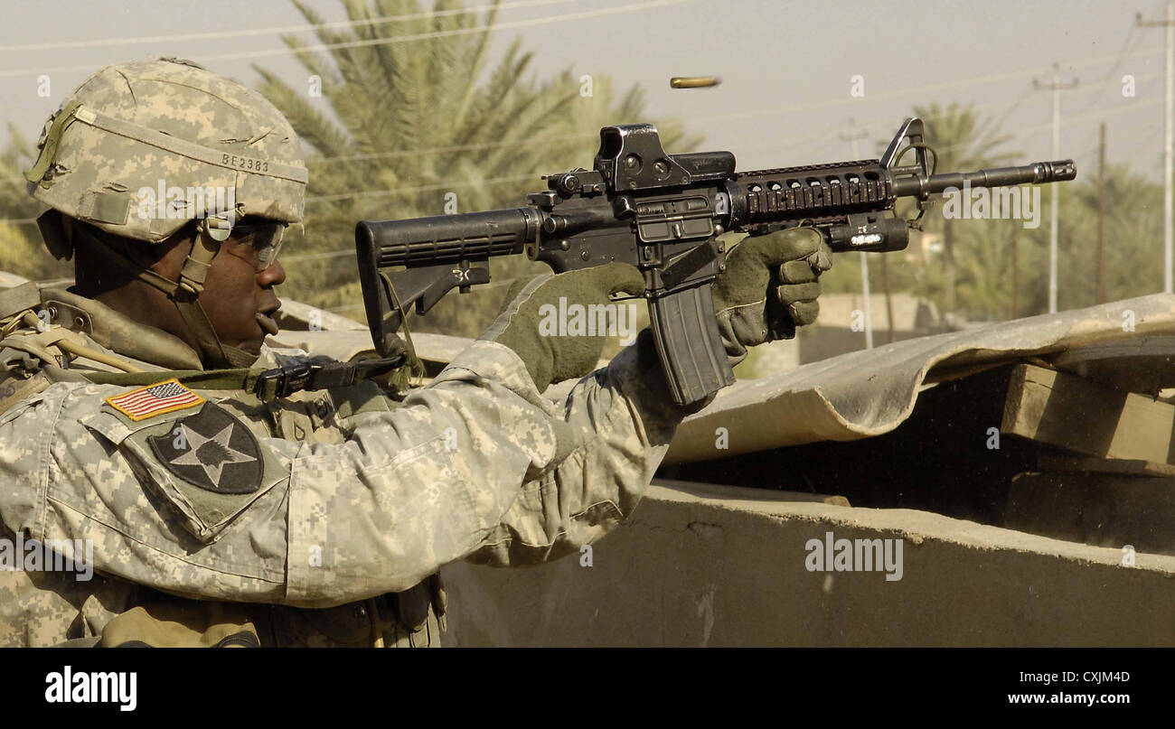 US Army soldiers from the 1st Stryker Brigade Combat Team return fire on insurgents from a rooftop March 14, 2007 in Buhriz, Iraq. Stock Photo