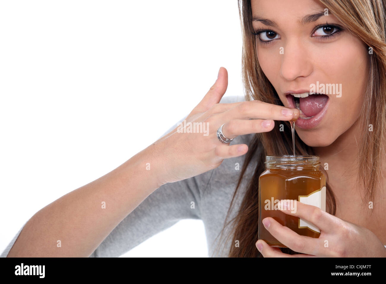 Brunette dipping finger in honey jar Stock Photo