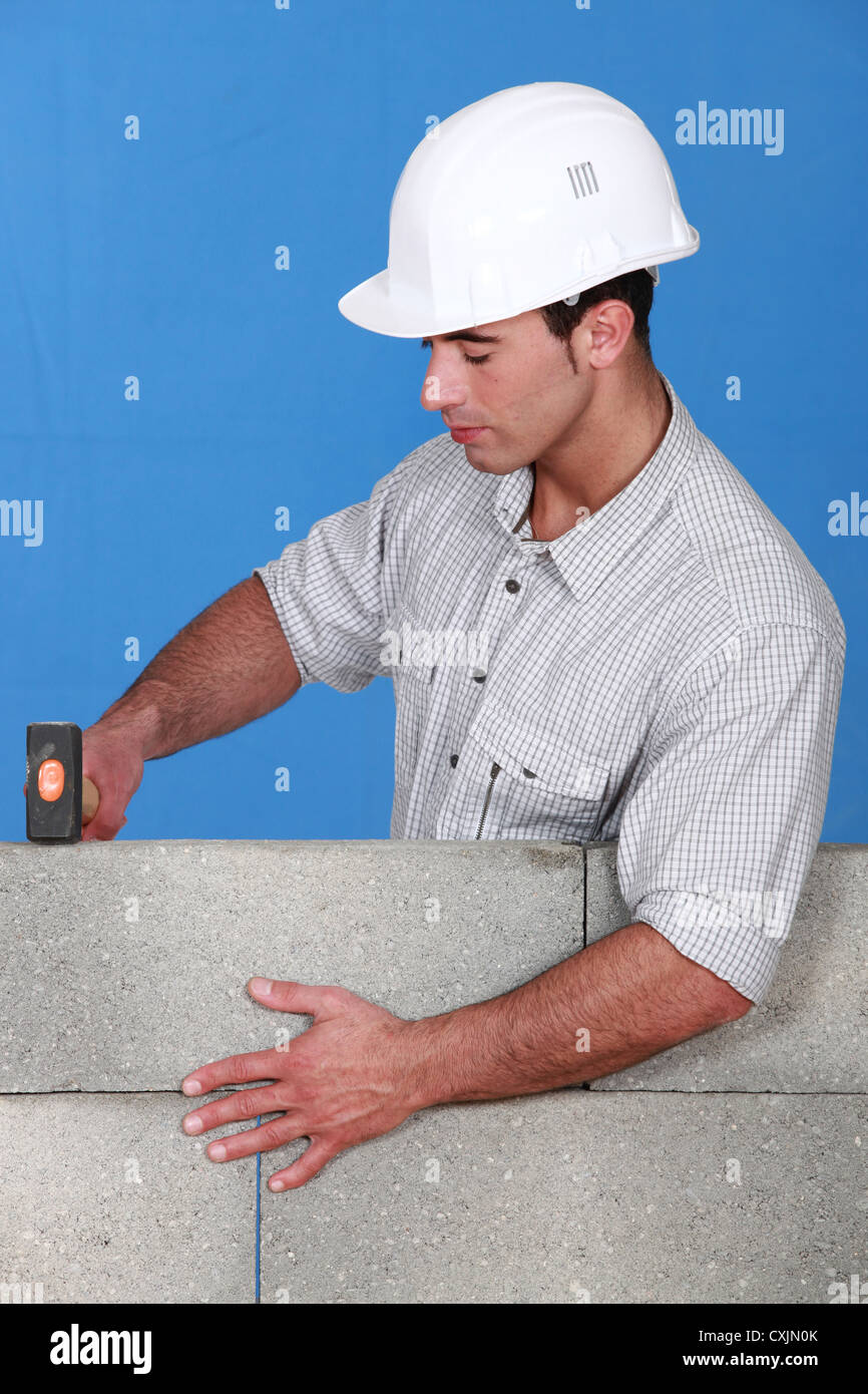 Bricklayer tapping down a block wall Stock Photo Alamy