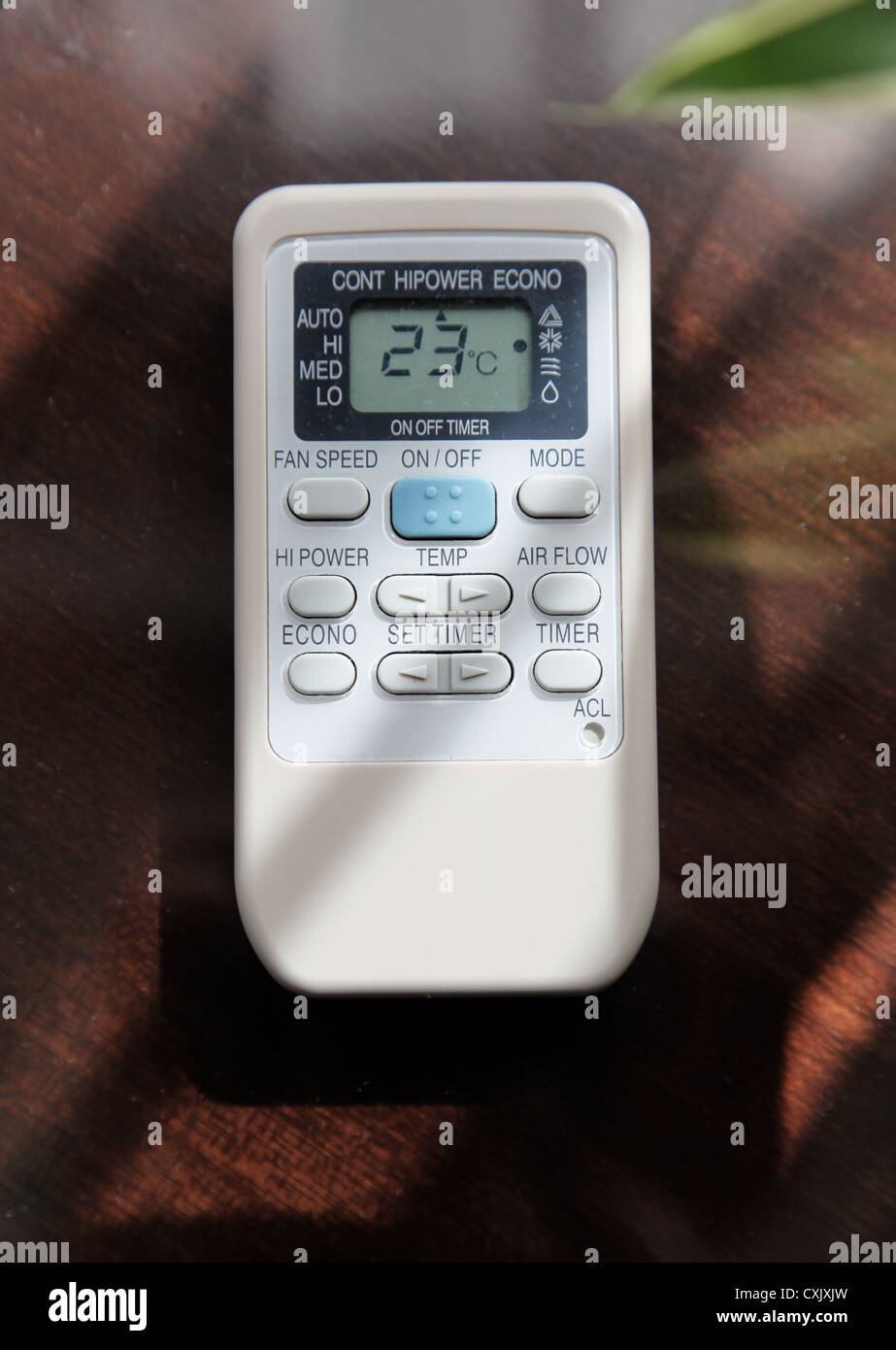 It's a photo of a remote control of the air conditioned in a room. It's stand on a wood table with a natural light. 23 degres Stock Photo
