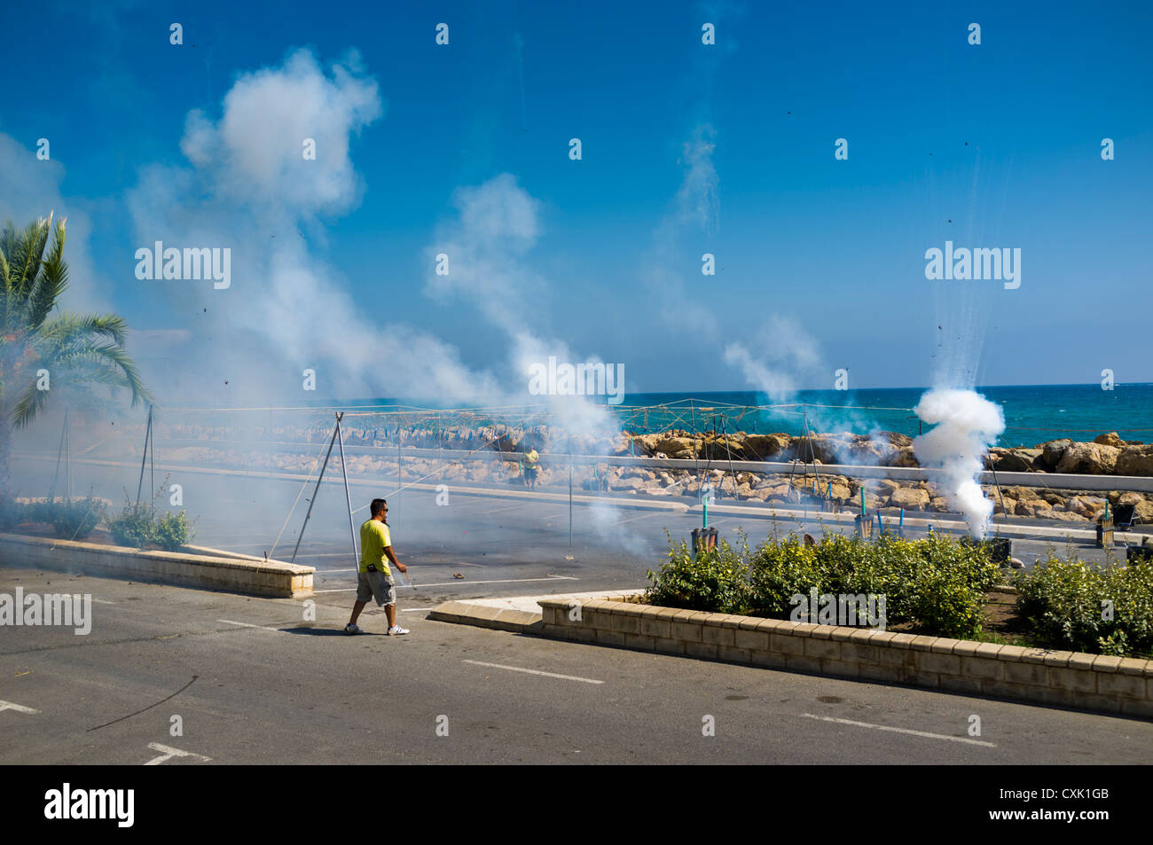A mascaleta daytime firework display during a Spanish fiesta in Altea is supervised by the man in the yellow tee-shirt. Stock Photo