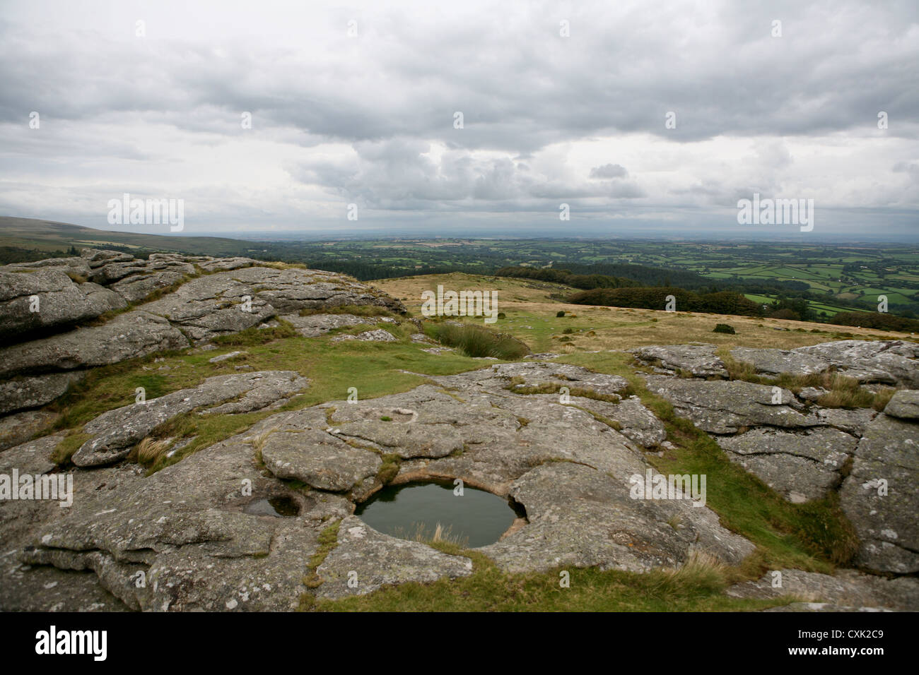 Far reaching view from the top of Kestor Rock, with water filled rock basin / pool in foreground, Dartmoor National Park, UK Stock Photo