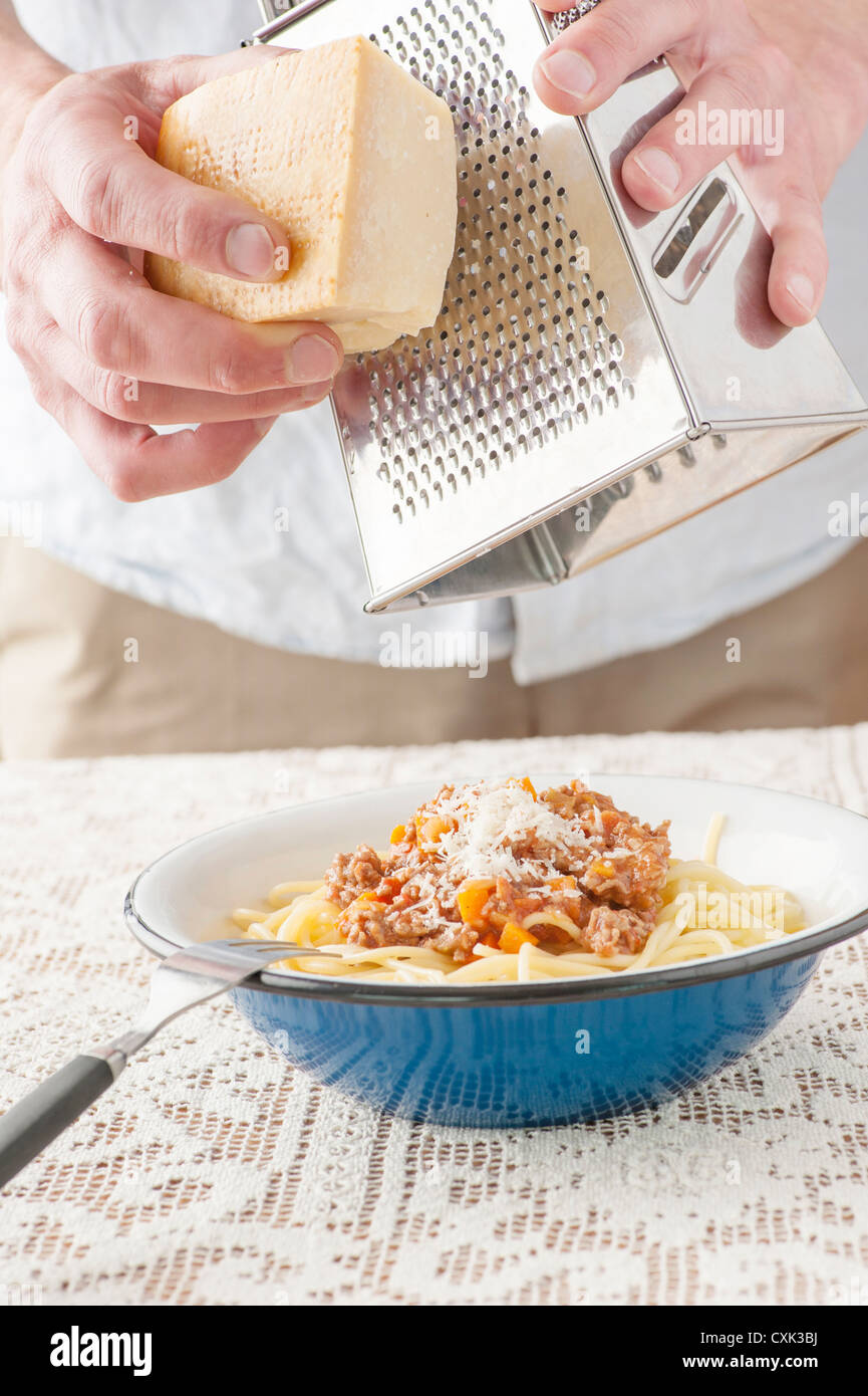 Serving of pasta bolognaise. The chef is adding grated parmesan cheese on top. Stock Photo