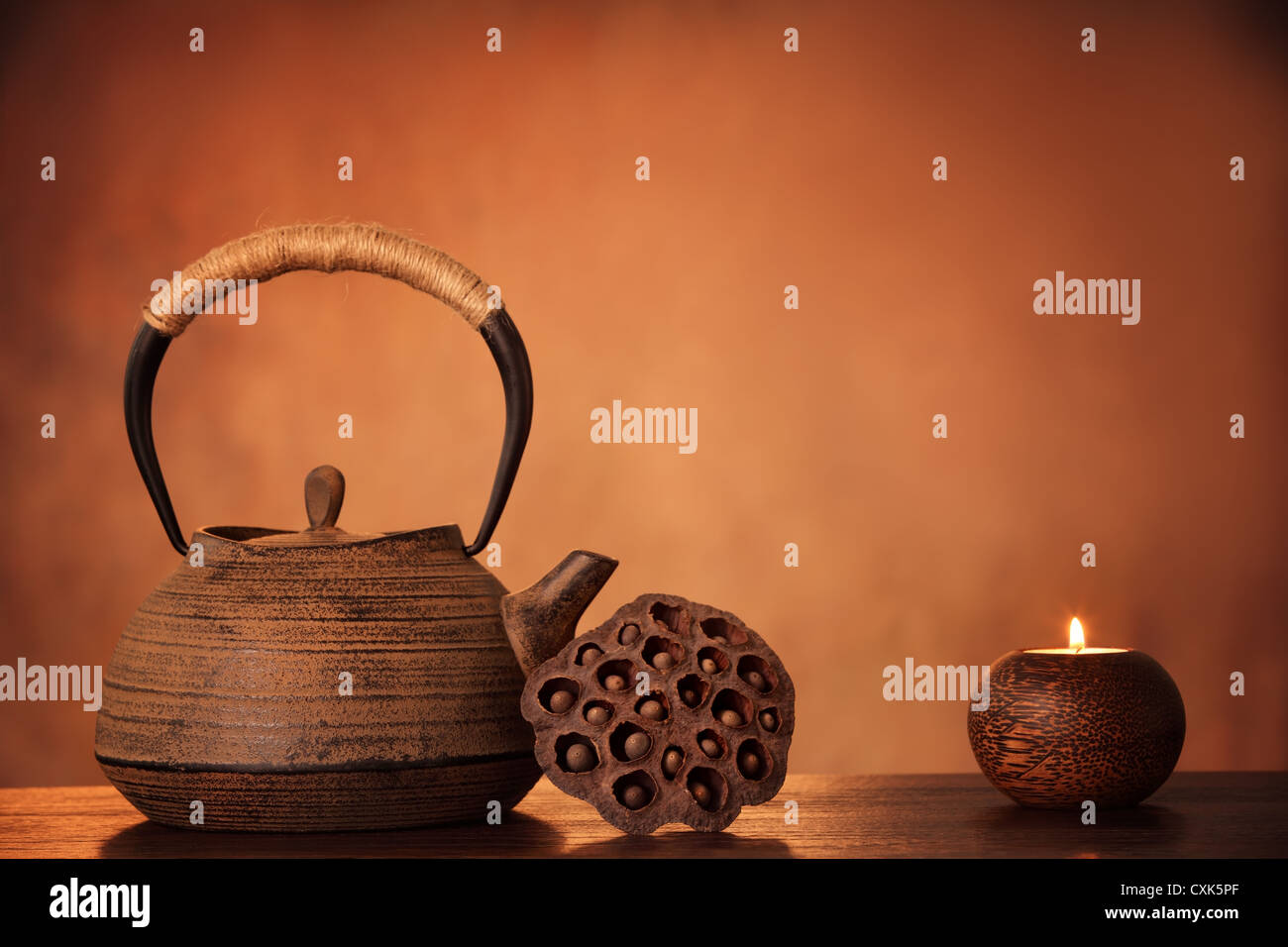 Black iron asian teapot and burning candle,vintage style. Stock Photo