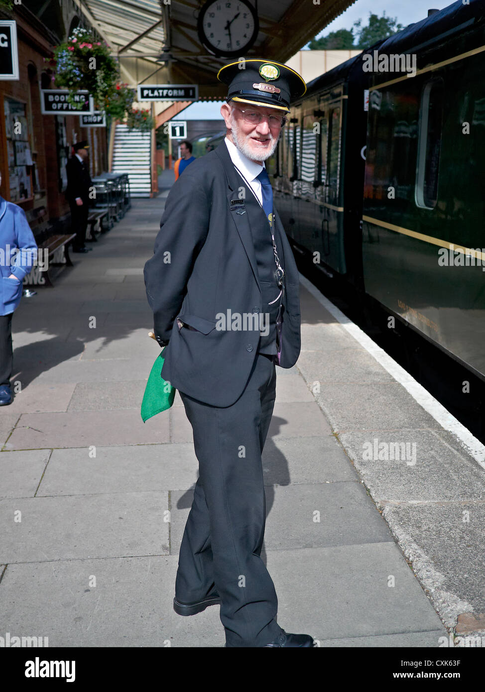 Train guard standing on the platform with awaiting train. Toddington Historic train station Gloucestershire  England UK Stock Photo