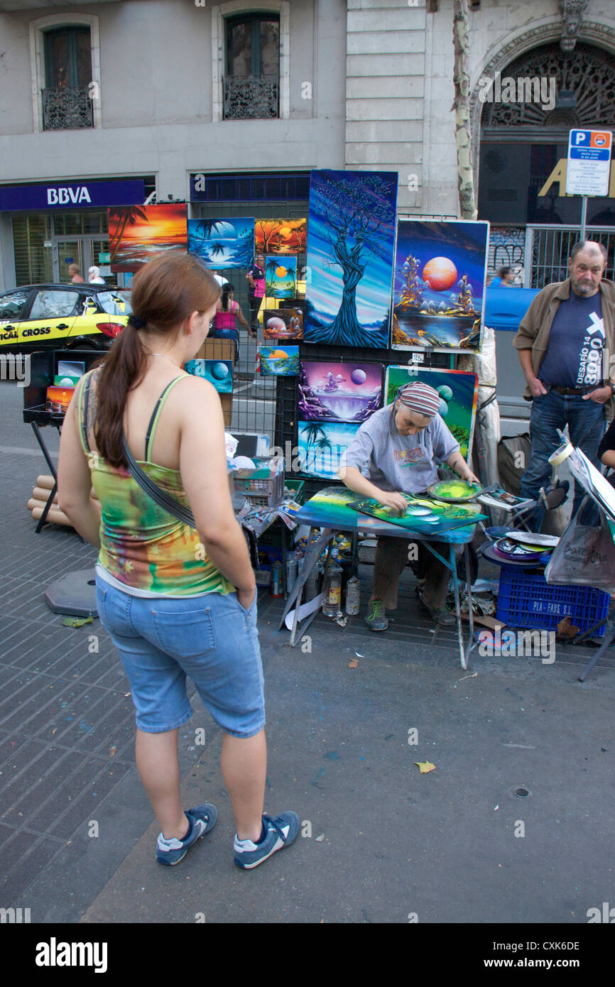 tourists watching lady artist,painter making beautiful drawings in public in the las ramblas street in barcelona.spain,europe Stock Photo