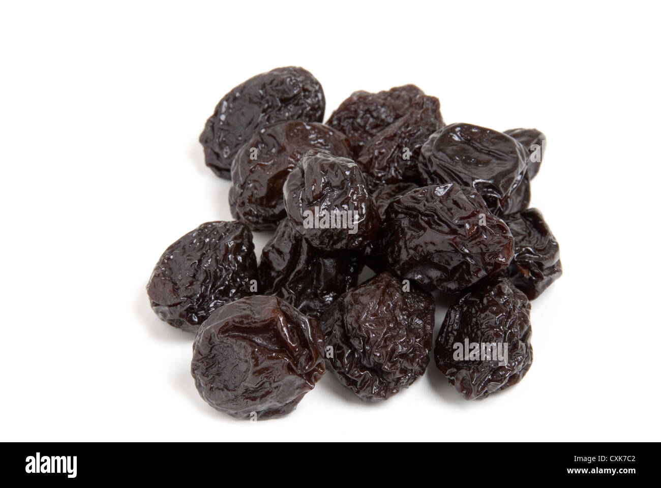 A pile of dried plums or prunes on a white background. Stock Photo