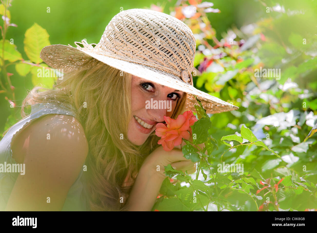 Woman smelling a rose in the garden Stock Photo - Alamy