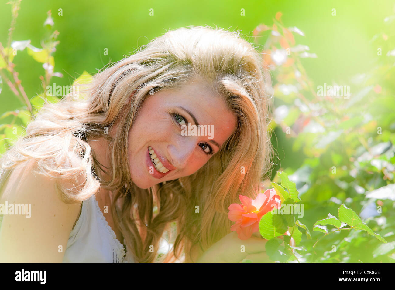 Woman smelling a rose in the garden Stock Photo - Alamy