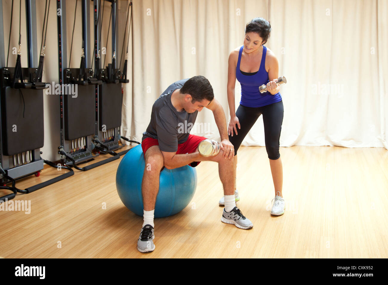 A man is working out with a female personal trainer. Stock Photo
