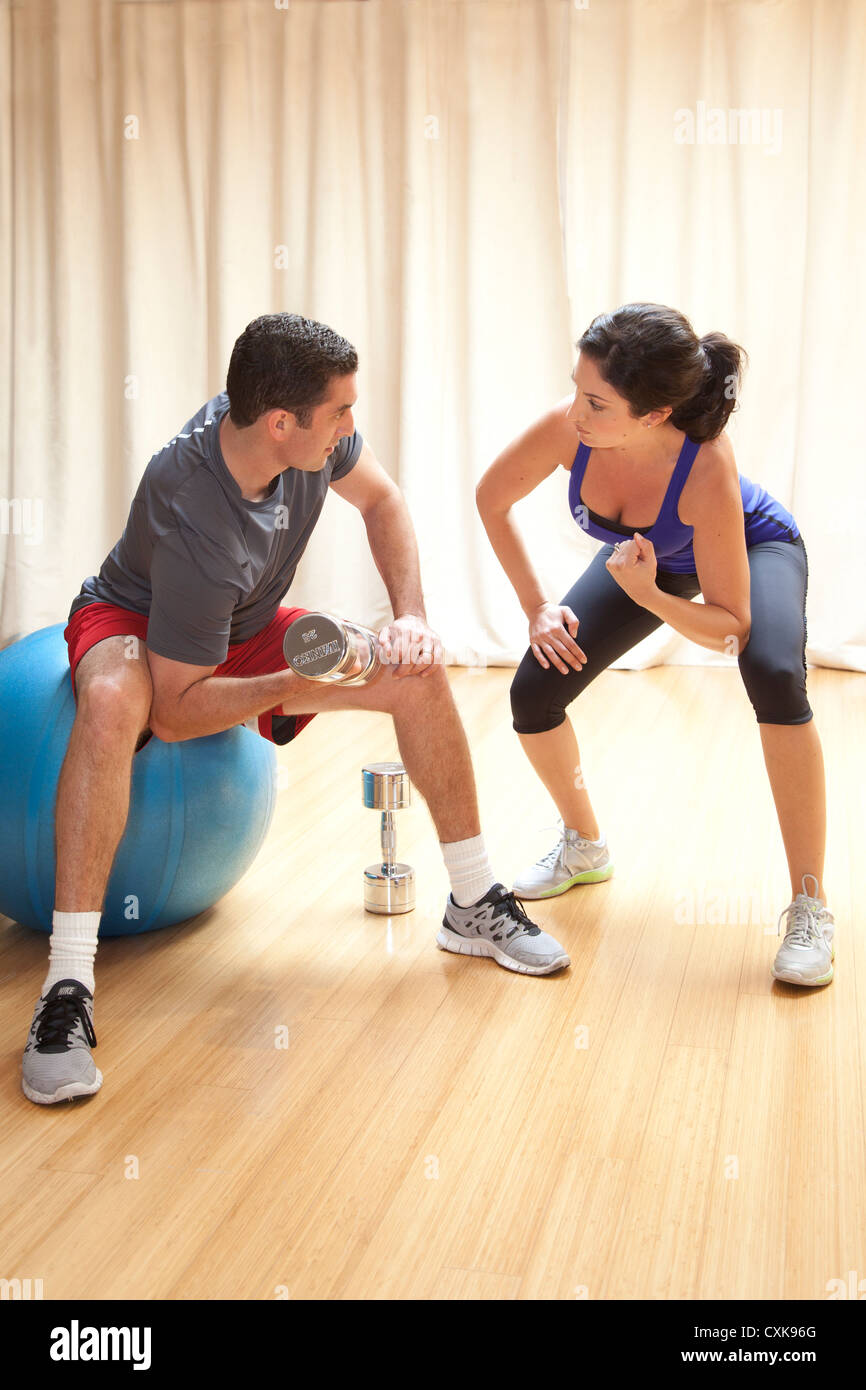 A man is working out with a female personal trainer. Stock Photo