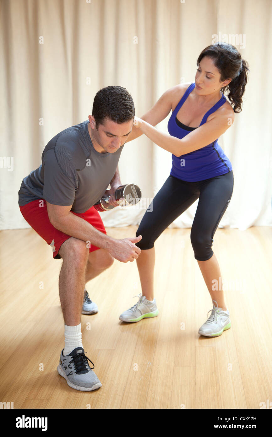 A man is working out with a female personal trainer. Stock Photo