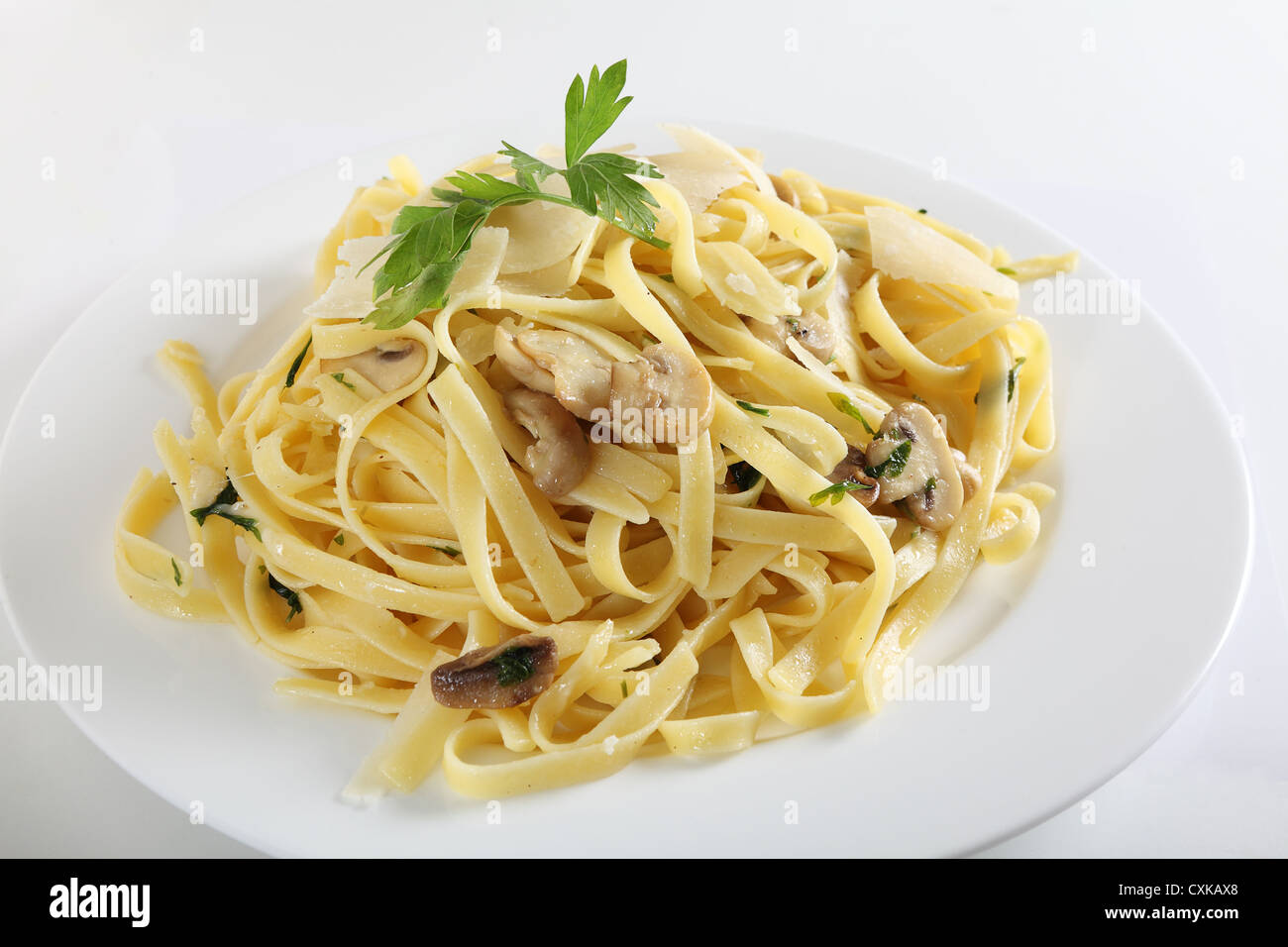 Ribbon pasta with mushrooms and italian parsley, fettuccine ai funghi, topped with curls of parmesan reggiano Stock Photo