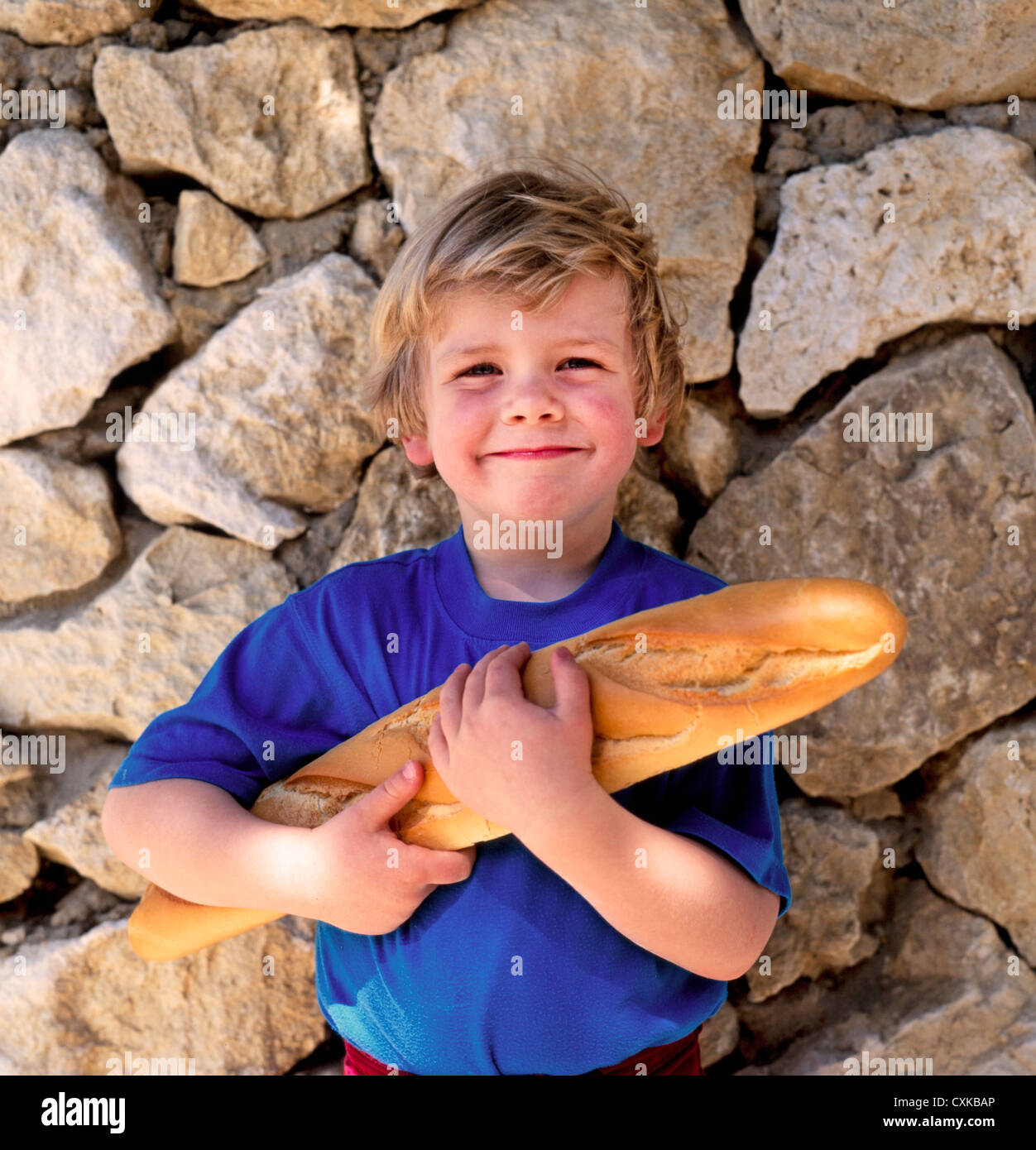 YOUNG BOY HOLDING FRENCH BREAD BAGUETTE Stock Photo