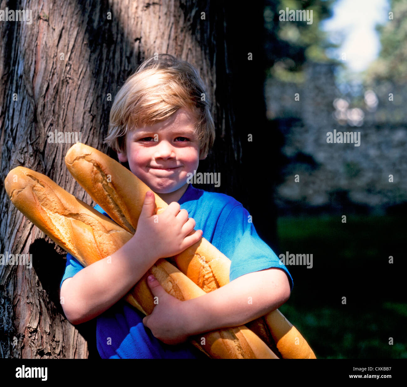 YOUNG BOY HOLDING FRENCH BREAD BAGUETTES Stock Photo